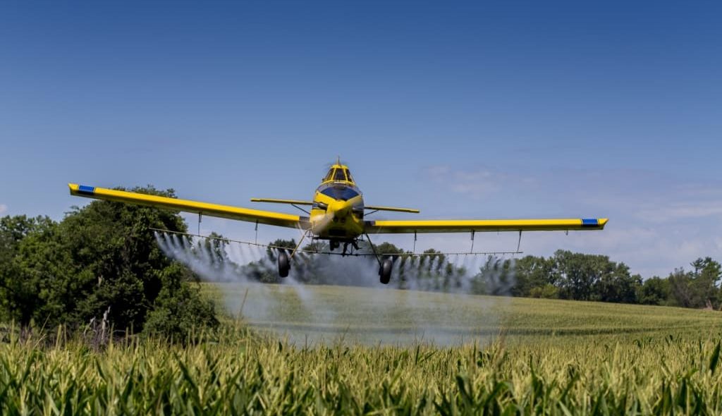 Avião agrícola aplicando defensivos na lavoura