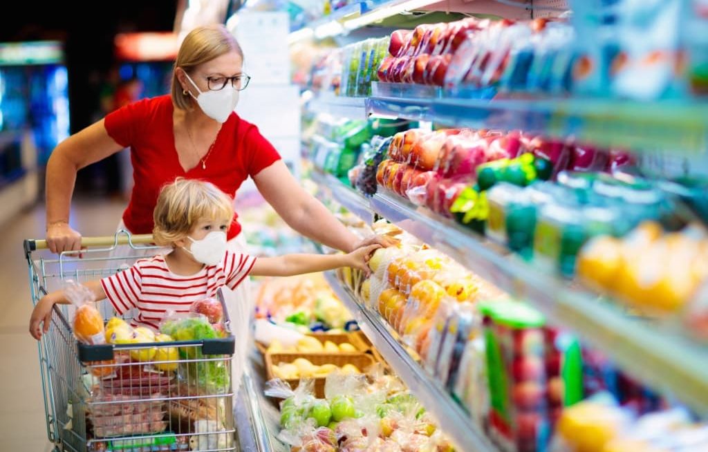 Mãe e filho com máscaras comprando alimentos no supermercado
