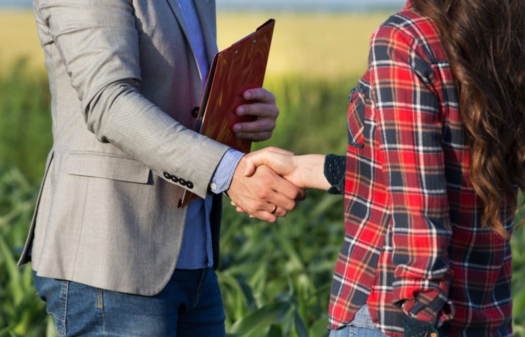 Agricultora dando a mão para agente de seguros