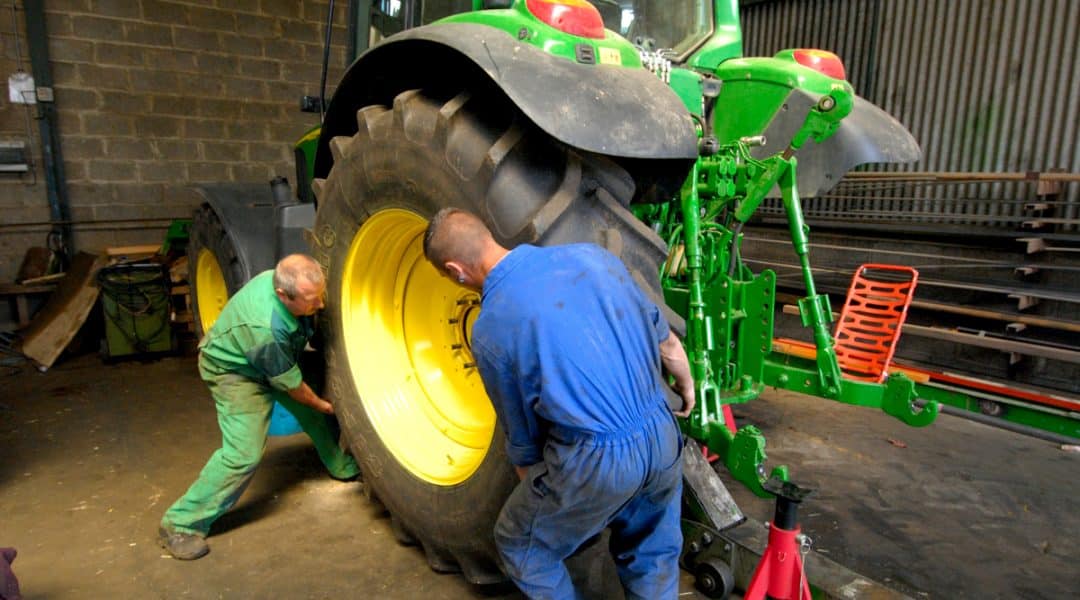 Homens trocando pneu de trator