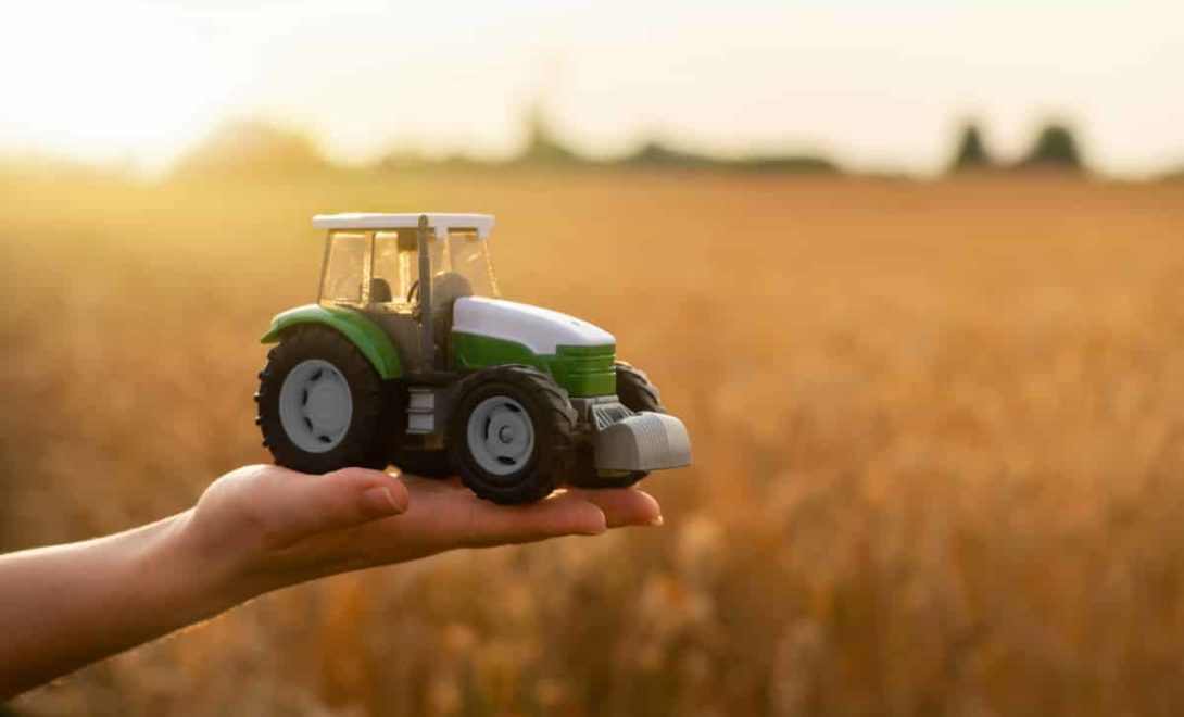 Mão segurando mini trator, simbolizando o cuidado com as maquinas agricolas