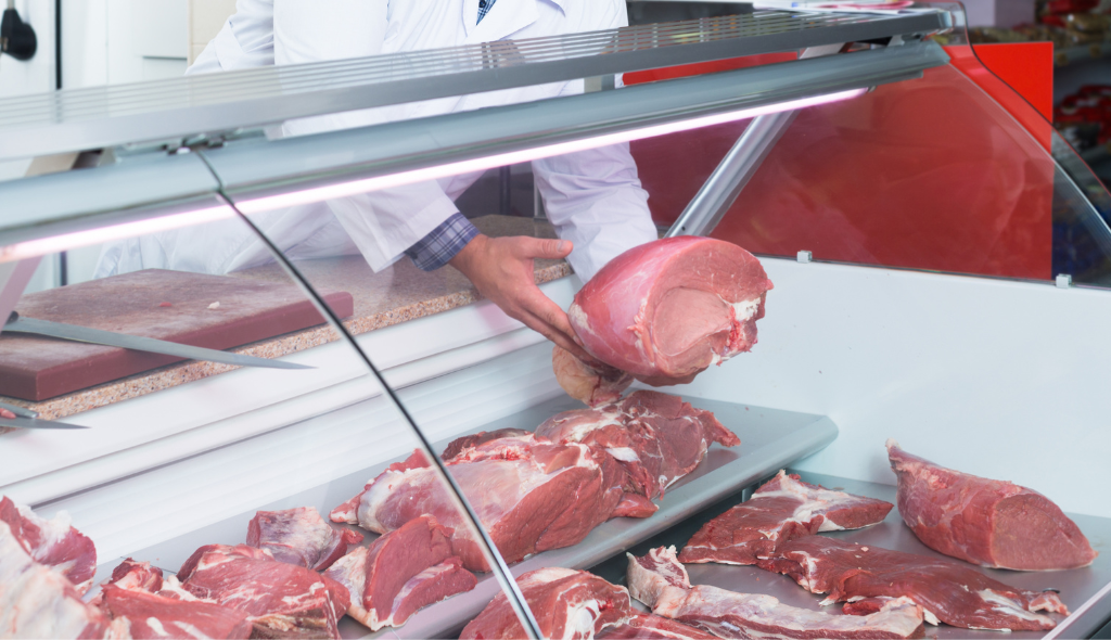 Homem colocando corte de carne halal em vitrine de frigorífico para venda