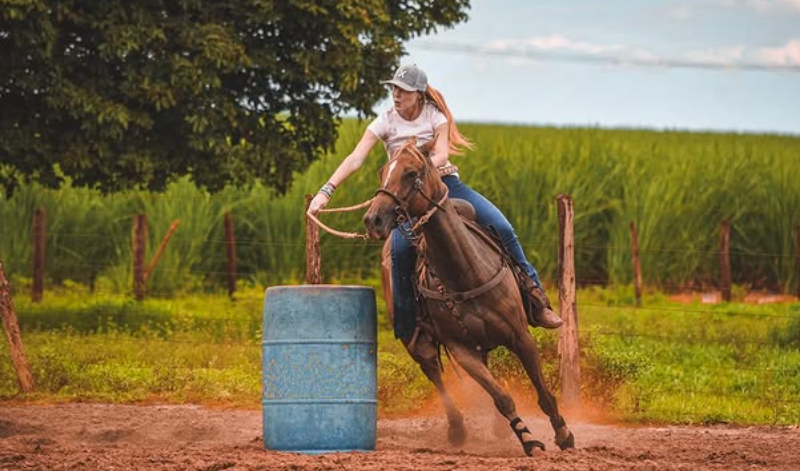 Nicoli Fittipaldi montada em um cavalo durante uma prova de Tr&ecirc;s Tambores, contornando um tambor azul em uma pista de terra, com vegeta&ccedil;&atilde;o ao fundo